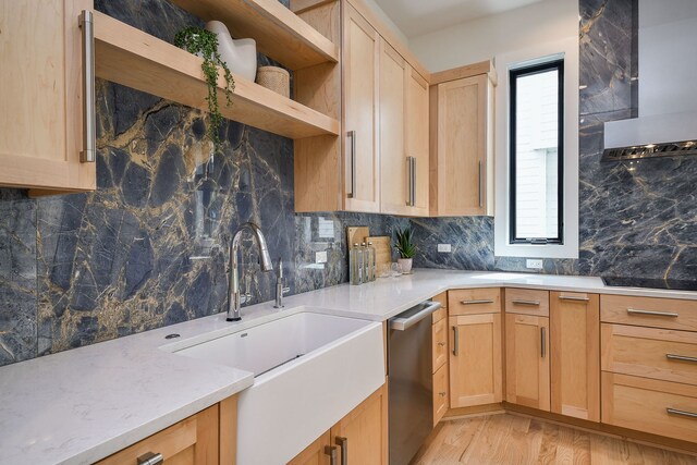kitchen with wall chimney range hood, dishwasher, light brown cabinets, and a sink