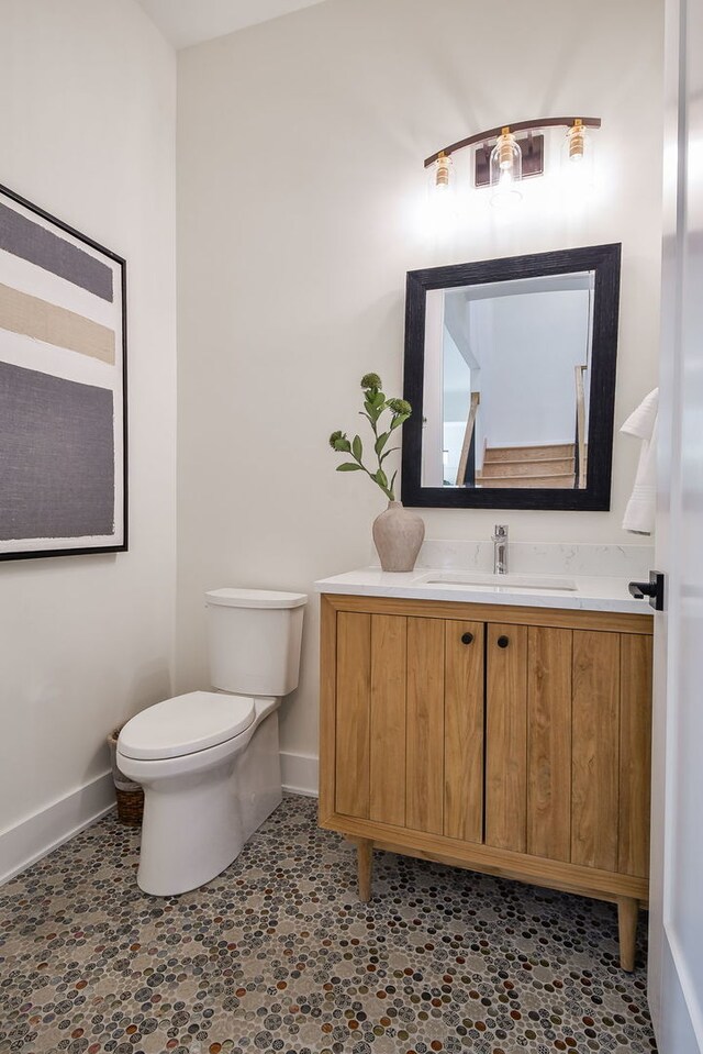 bathroom with baseboards, toilet, and vanity