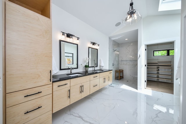 full bathroom featuring marble tiled flooring, a marble finish shower, lofted ceiling, and double vanity