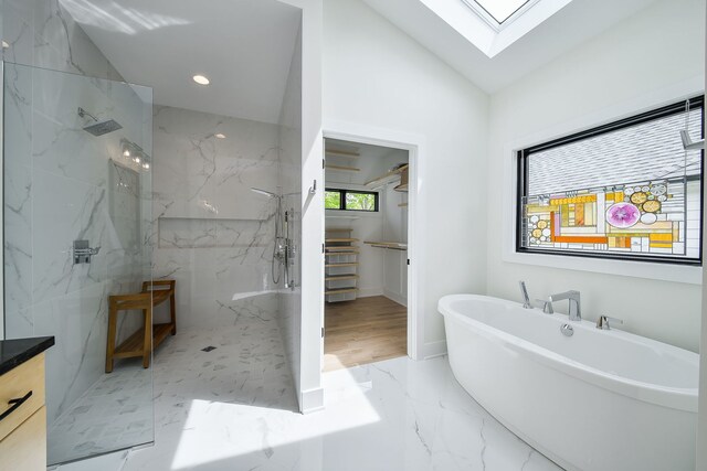 full bath with a marble finish shower, a skylight, a freestanding bath, marble tiled flooring, and lofted ceiling