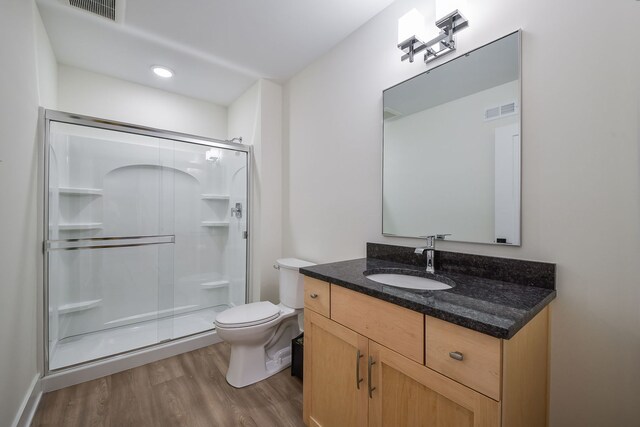 full bathroom with wood finished floors, a shower stall, toilet, and vanity