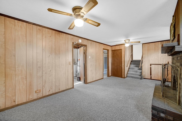 588 Renee Dr, South Elgin, IL 60177 - unfurnished living room featuring a ceiling fan, carpet floors, wood walls, stairway, and ornamental molding