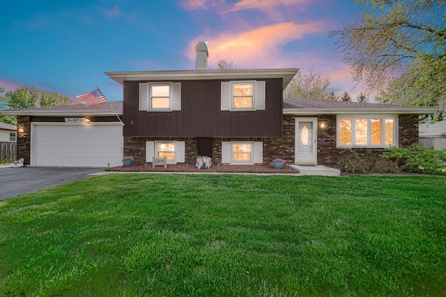 588 Renee Dr, South Elgin, IL 60177 - split level home featuring a chimney, a lawn, asphalt driveway, an attached garage, and brick siding