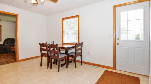 dining space with a drop ceiling, baseboards, and a ceiling fan