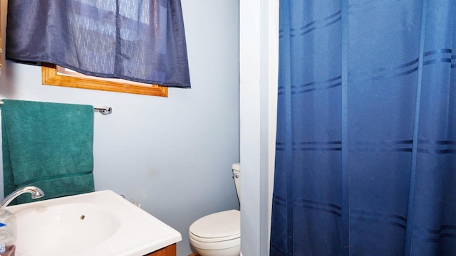 bathroom featuring toilet, vanity, and a shower with curtain