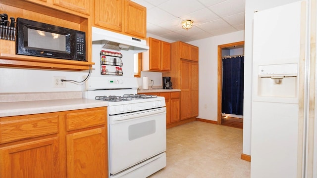kitchen with white range with gas stovetop, under cabinet range hood, black microwave, light countertops, and a paneled ceiling