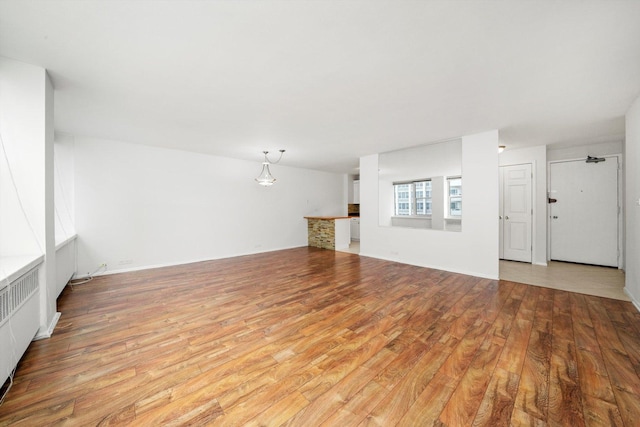 unfurnished living room featuring radiator and light wood-type flooring