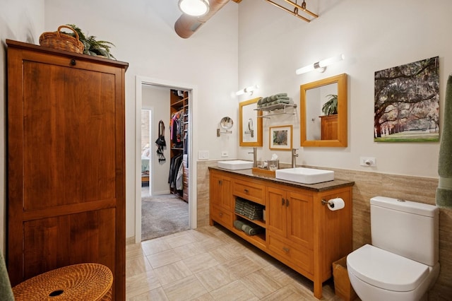 full bathroom featuring toilet, double vanity, a ceiling fan, a spacious closet, and tile patterned floors