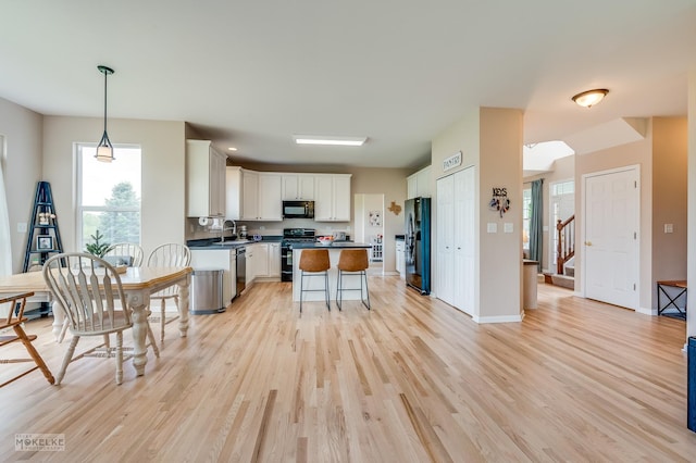 241 Morgan Valley Dr, Oswego, IL 60543 - kitchen with black appliances, dark countertops, light wood-style flooring, and white cabinetry