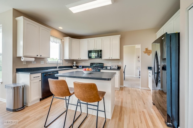 241 Morgan Valley Dr, Oswego, IL 60543 - kitchen with black appliances, light wood finished floors, white cabinetry, dark countertops, and a kitchen island