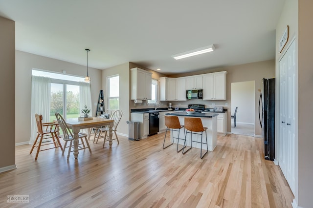 241 Morgan Valley Dr, Oswego, IL 60543 - kitchen featuring black appliances, a kitchen island, light wood-style floors, baseboards, and white cabinets
