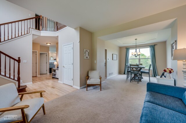 241 Morgan Valley Dr, Oswego, IL 60543 - living area with stairs, a chandelier, light carpet, and baseboards