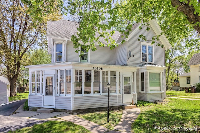 10208 N Main St, Richmond, IL 60071 - view of front of house with a sunroom, a shingled roof, entry steps, and a front yard