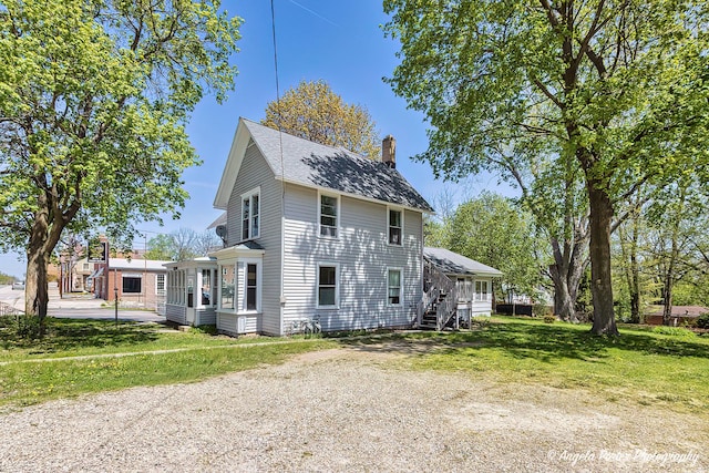 10208 N Main St, Richmond, IL 60071 - view of side of home featuring a chimney, stairway, and a lawn