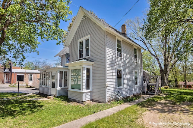 10208 N Main St, Richmond, IL 60071 - view of side of property with a sunroom, a chimney, a lawn, and a deck