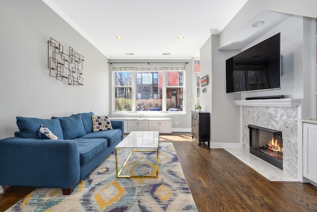 living room with ornamental molding, baseboards, wood finished floors, a high end fireplace, and recessed lighting
