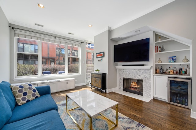 living room featuring beverage cooler, ornamental molding, dark wood-style flooring, a premium fireplace, and recessed lighting