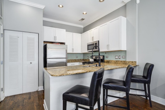kitchen featuring appliances with stainless steel finishes, a peninsula, recessed lighting, light stone counters, and tasteful backsplash