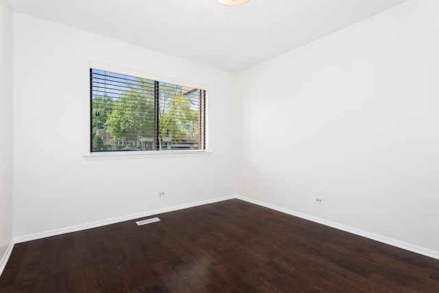 spare room with dark wood-type flooring and baseboards