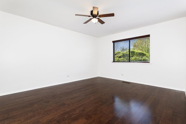 spare room with baseboards, dark wood-style flooring, and a ceiling fan