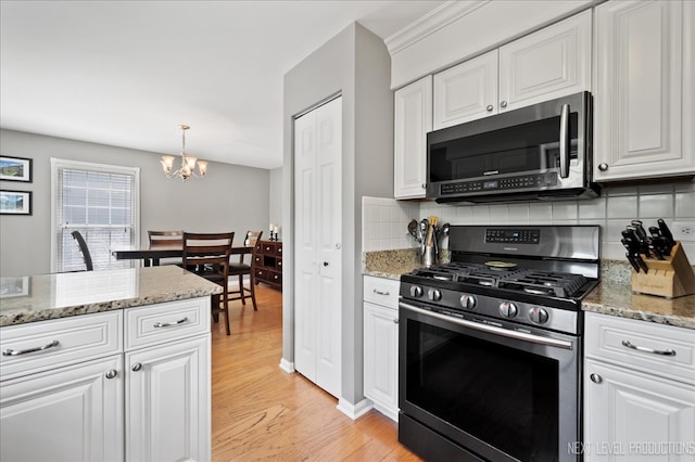 311 Mayfair Ln, South Elgin, IL 60177 - kitchen with appliances with stainless steel finishes, a chandelier, light wood-style flooring, decorative backsplash, and white cabinetry