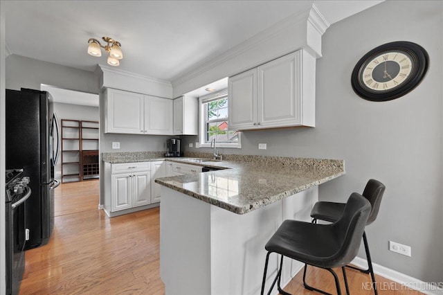 311 Mayfair Ln, South Elgin, IL 60177 - kitchen with a peninsula, range with gas stovetop, a sink, white cabinets, and ornamental molding