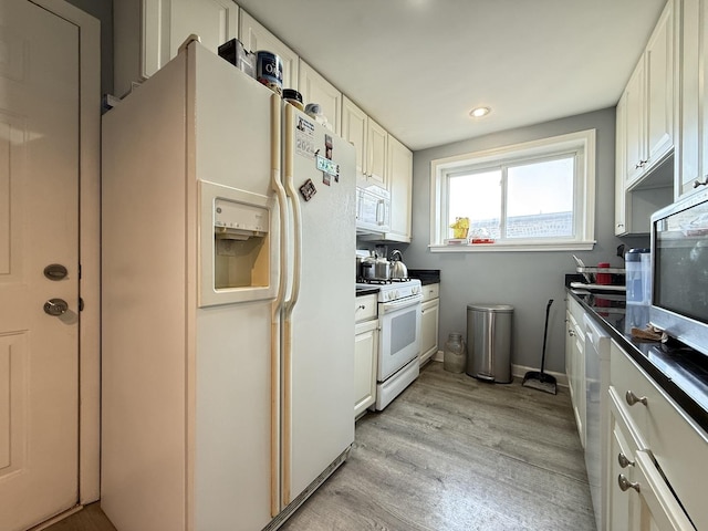 kitchen with white appliances, dark countertops, light wood-type flooring, white cabinets, and recessed lighting