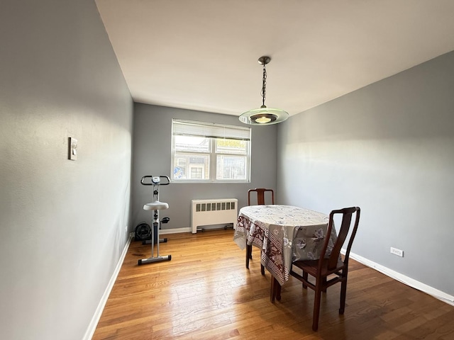 dining room with radiator heating unit, wood finished floors, and baseboards