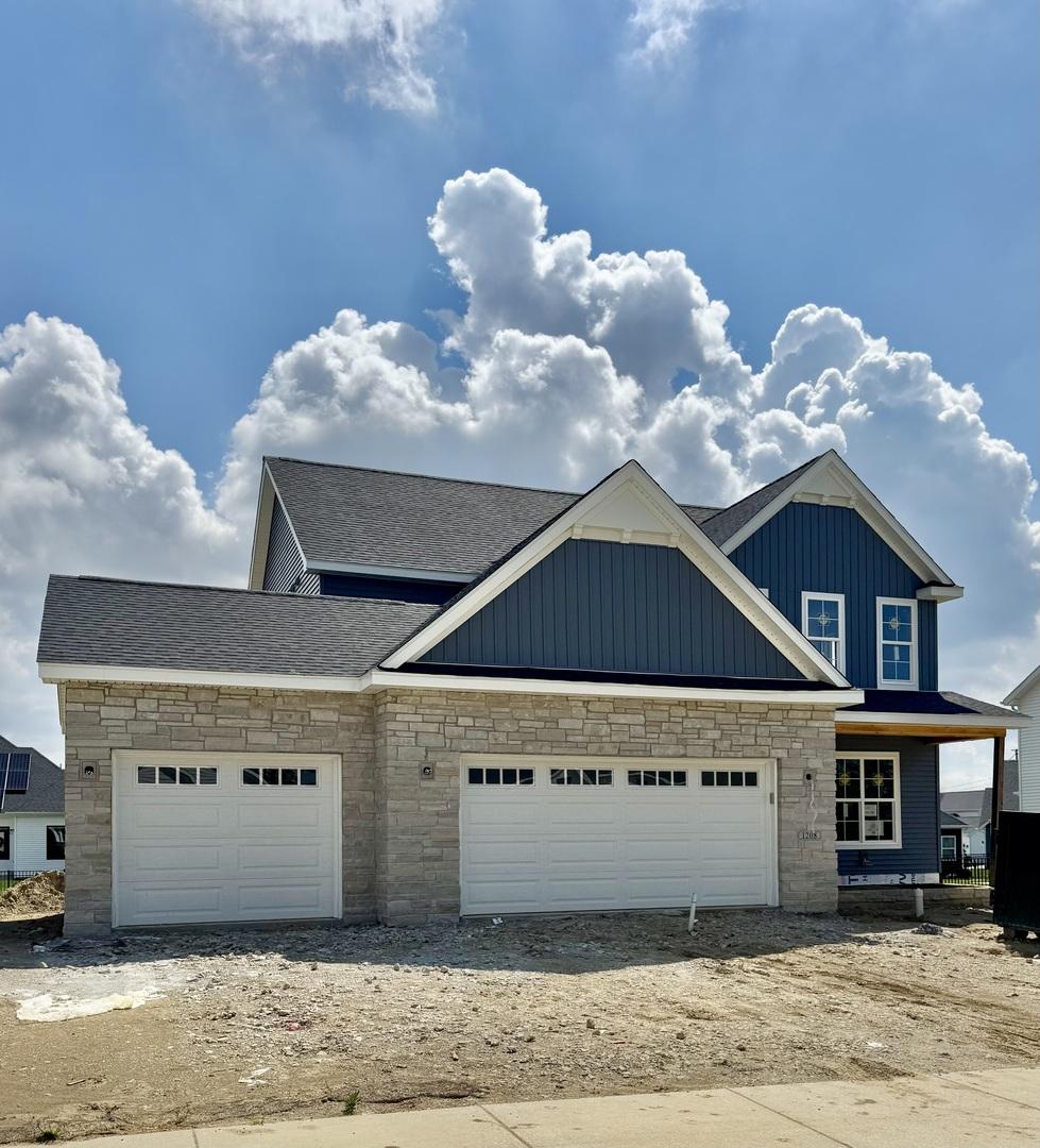 view of front of home with board and batten siding, stone siding, a shingled roof, and an attached garage