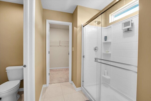 6103 Winterhaven Dr, Joliet, IL 60431 - bathroom featuring a shower stall, toilet, tile patterned flooring, a spacious closet, and baseboards