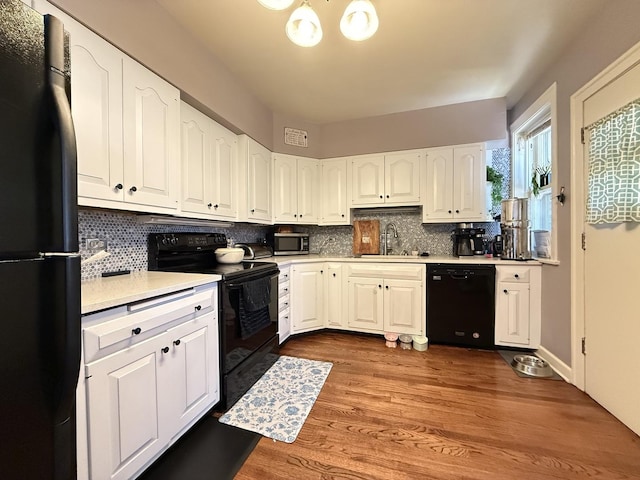 kitchen with black appliances, a sink, decorative backsplash, and light countertops