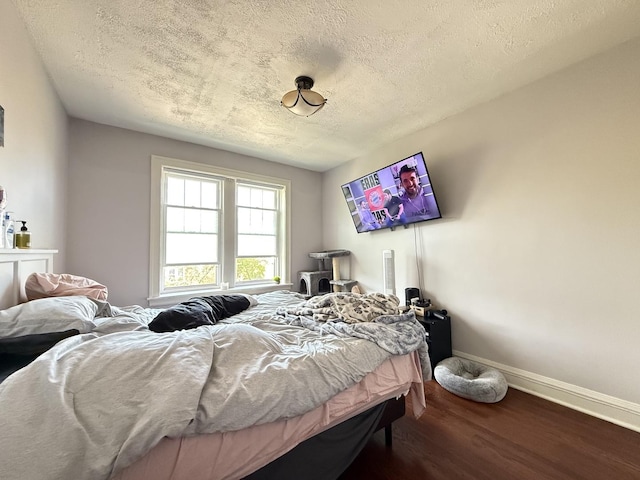 bedroom featuring a textured ceiling, wood finished floors, and baseboards