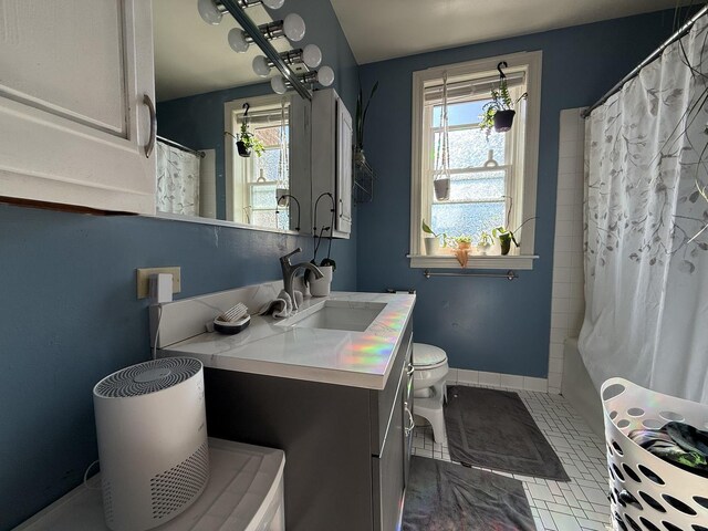 bathroom featuring plenty of natural light, vanity, toilet, and baseboards
