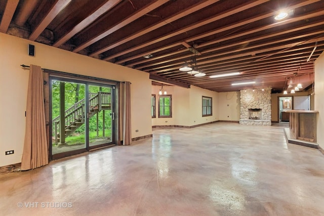 1302 Bradley Ct, Spring Grove, IL 60081 - unfurnished living room featuring concrete floors, healthy amount of natural light, baseboards, and a stone fireplace