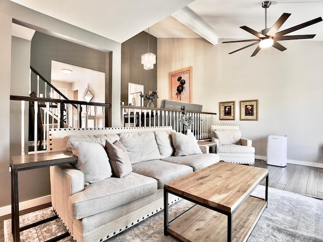 living area with stairway, wood finished floors, ceiling fan, baseboards, and beamed ceiling