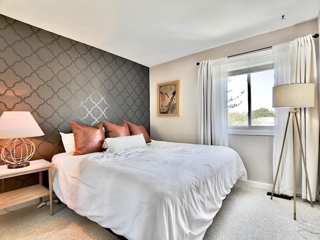carpeted bedroom with an accent wall, wallpapered walls, and baseboards