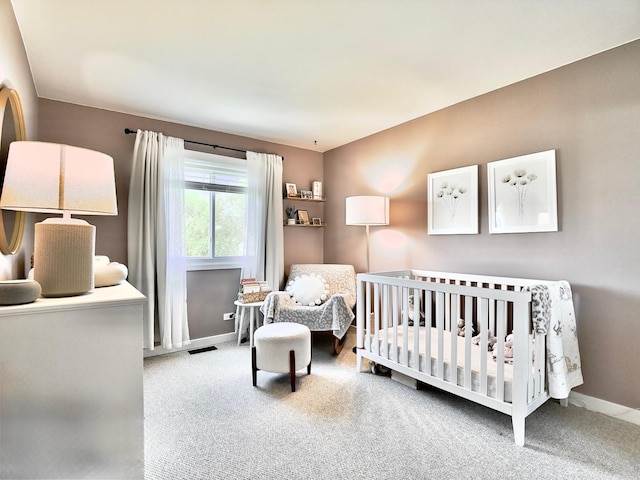 carpeted bedroom with baseboards and a nursery area