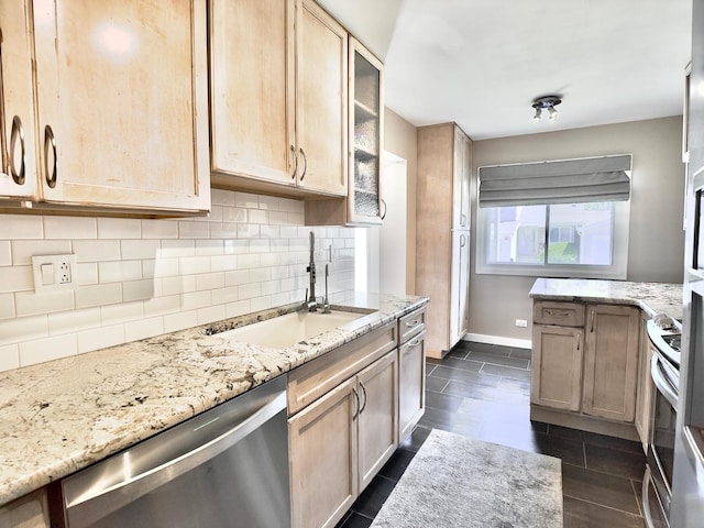 kitchen featuring appliances with stainless steel finishes, a sink, light stone countertops, and tasteful backsplash