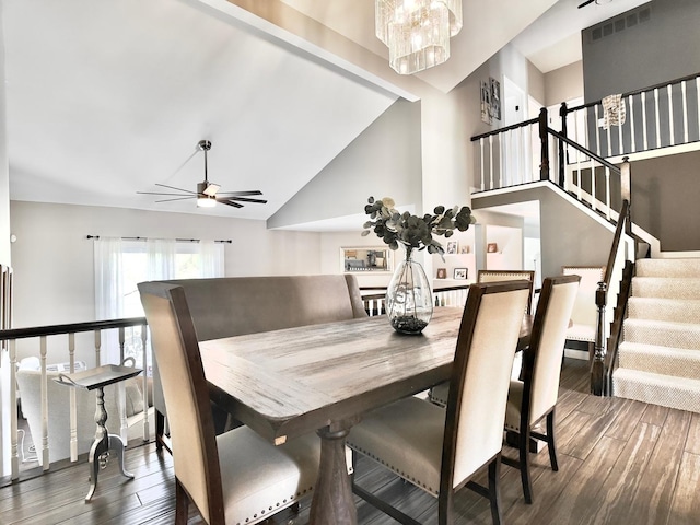 dining room with wood finished floors, stairway, ceiling fan, a chandelier, and high vaulted ceiling