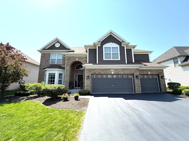 12074 Winterberry Ln, Plainfield, IL 60585 - traditional home with asphalt driveway, a front yard, brick siding, and an attached garage