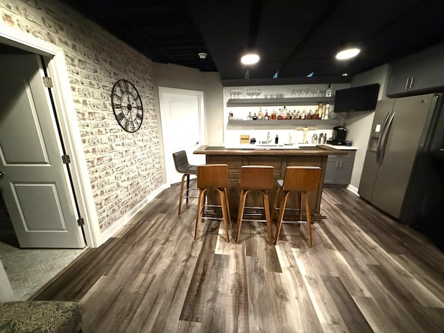 12074 Winterberry Ln, Plainfield, IL 60585 - indoor wet bar with stainless steel fridge, dark wood-style floors, brick wall, and baseboards