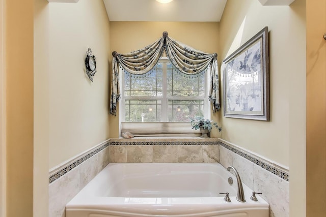 bathroom with a garden tub, a wainscoted wall, and tile walls