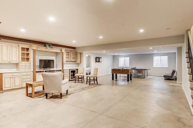 living area with finished concrete flooring, recessed lighting, beverage cooler, and baseboards