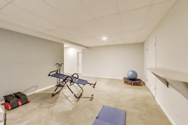 exercise room with a paneled ceiling and baseboards