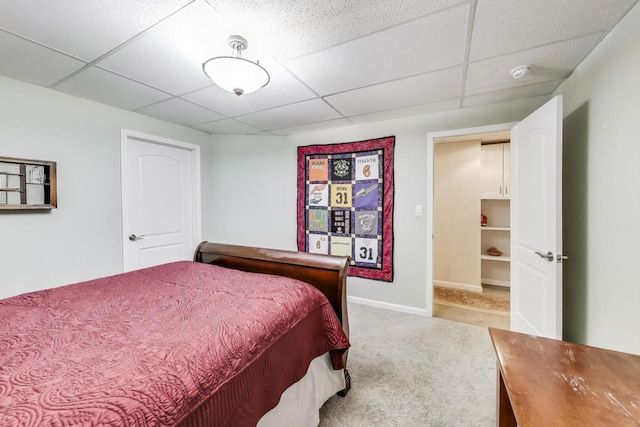 carpeted bedroom with a drop ceiling and baseboards