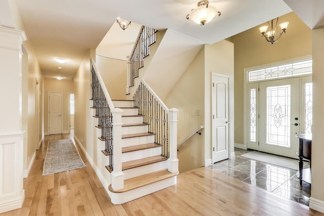 foyer with healthy amount of natural light, baseboards, stairs, and a chandelier