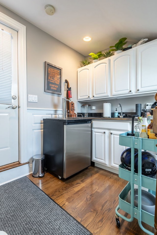 853 W Buckingham Pl Unit 4, Chicago, IL 60657 - kitchen featuring stainless steel dishwasher, dark countertops, dark wood-type flooring, white cabinets, and a wainscoted wall