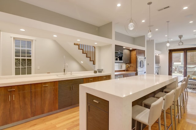 1942 N Cleveland Ave, Chicago, IL 60614 - kitchen featuring brown cabinetry, modern cabinets, a sink, light wood-style flooring, and recessed lighting