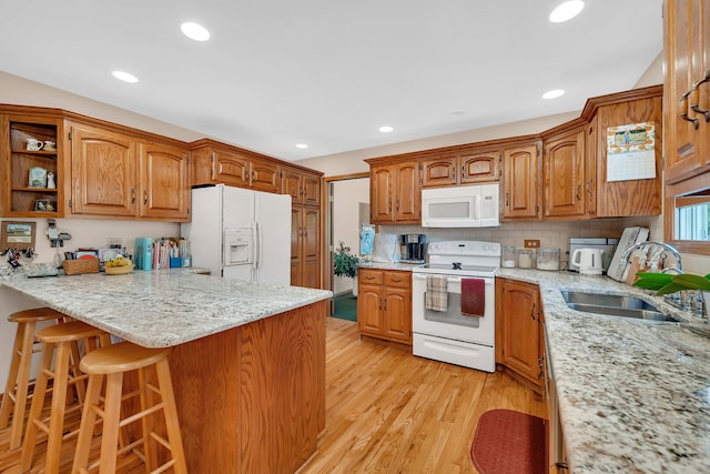 1002 Birchwood Ct, Morris, IL 60450 - kitchen featuring white appliances, a sink, a peninsula, a breakfast bar, and light wood-type flooring