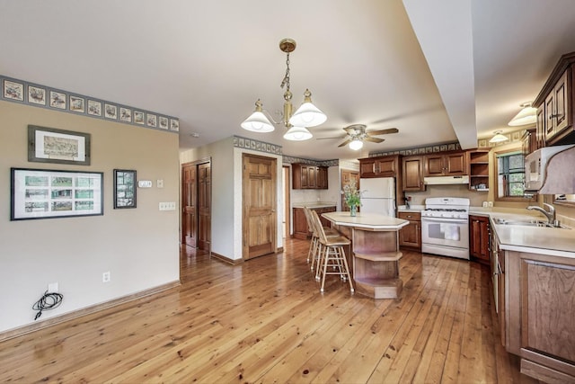 kitchen featuring white appliances, open shelves, a sink, under cabinet range hood, and light countertops
